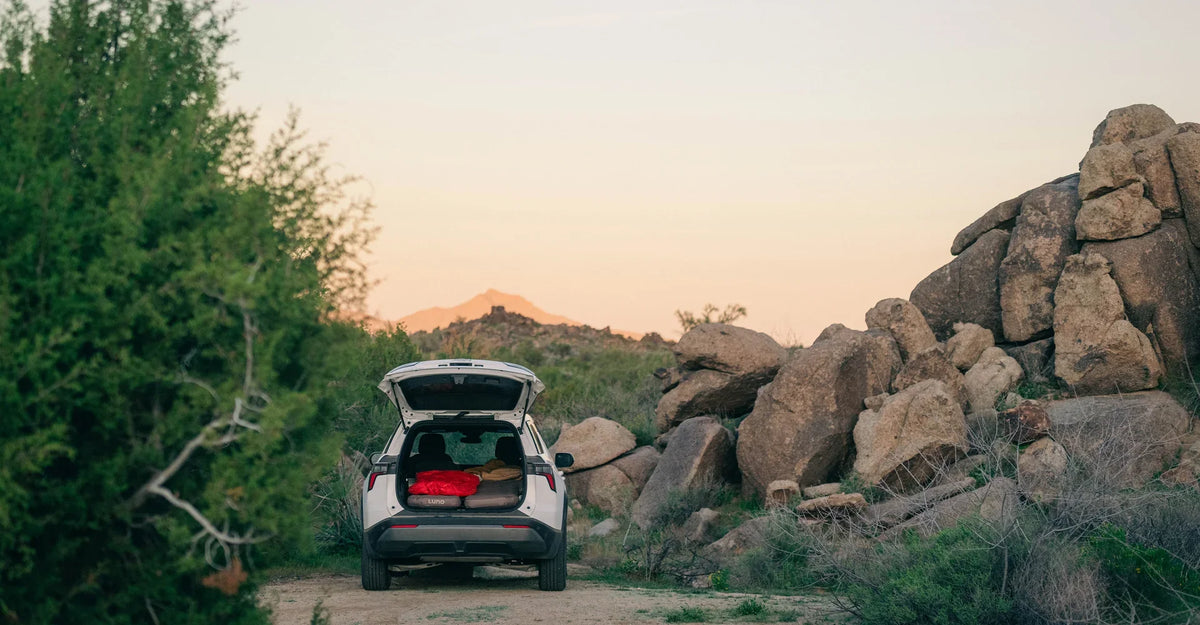 White Subaru with trunk open in a desert setting at sundown