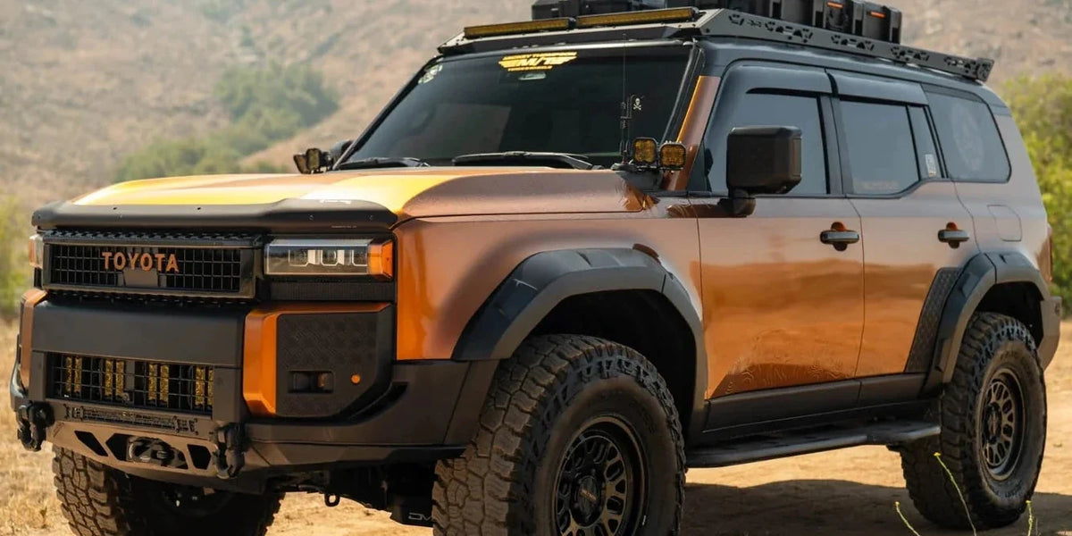 Orange Toyota Land Cruiser with a DV8 Offroad Spec Series roof rack on a dirt road