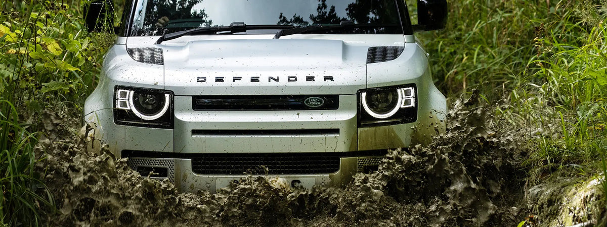 Land Rover Defender driving through a muddy trail