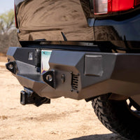 Close-up of a vehicle's rear bumper with off-road tire on a dirt road