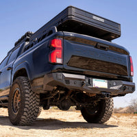 Black pickup truck with a roof rack and off-road tires in a desert setting