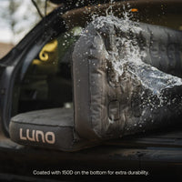 Car seat cover with 'LUNO' branding being splashed by water, with text about durability.
