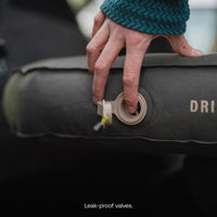 Hand adjusting a leak-proof valve on an inflatable pillow with 'Dri-Pillow' branding.