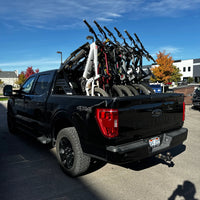 Black pickup truck with a bike rack loaded with bicycles on a street.