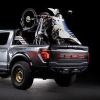Ford Raptor truck with a bike and motorcycle in the bed on a black background