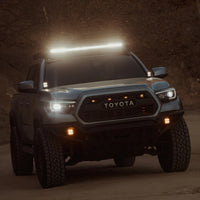 Toyota truck with LED light bar for off-road and overlanding at dusk on dirt road