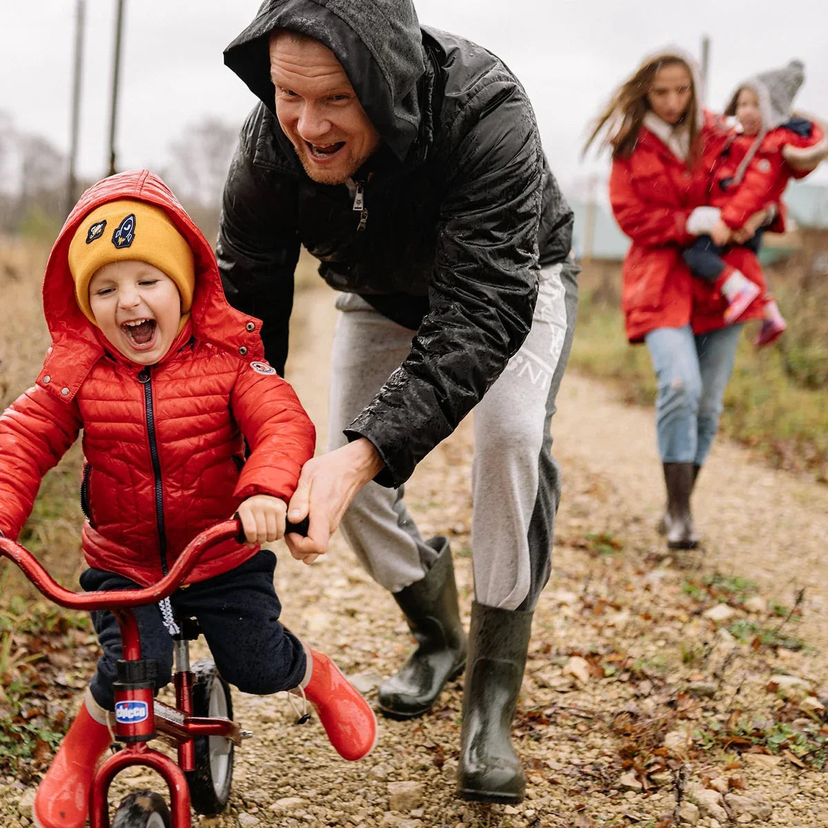 Child riding a balance bike with a parent on a family outing