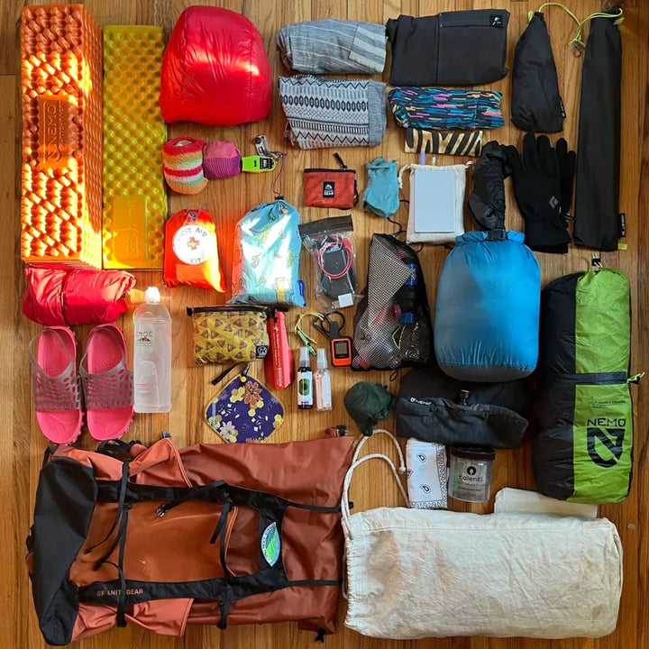 Backpacking gear laid out flat on a wooden floor before a trip