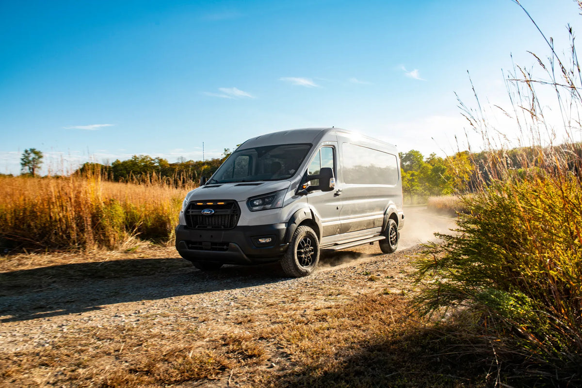 Ford Transit Van on a dirt trail in between tall grass
