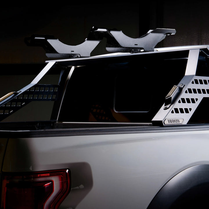 Two empty Big Days bike trays on the upper bar of a Chase Rack on a white pickup