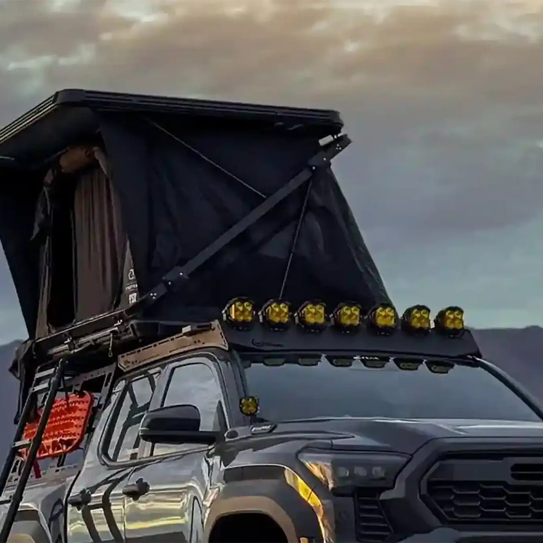 Toyota Tacoma with Free Spirit Evolution XL rooftop tent open on a bed rack in the mountains