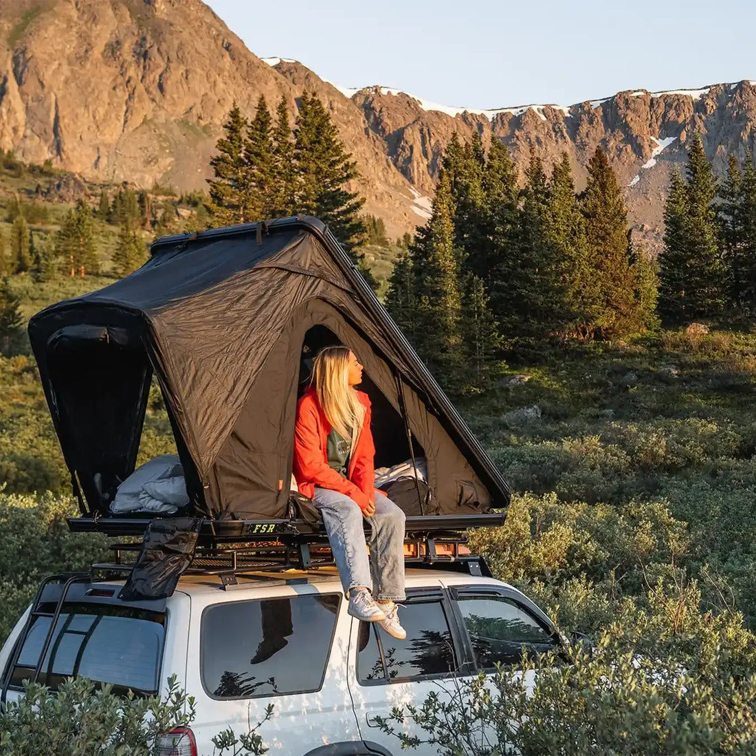 Camper sitting in an open Free Spirit Aspen Pro rooftop tent on a 4Runner