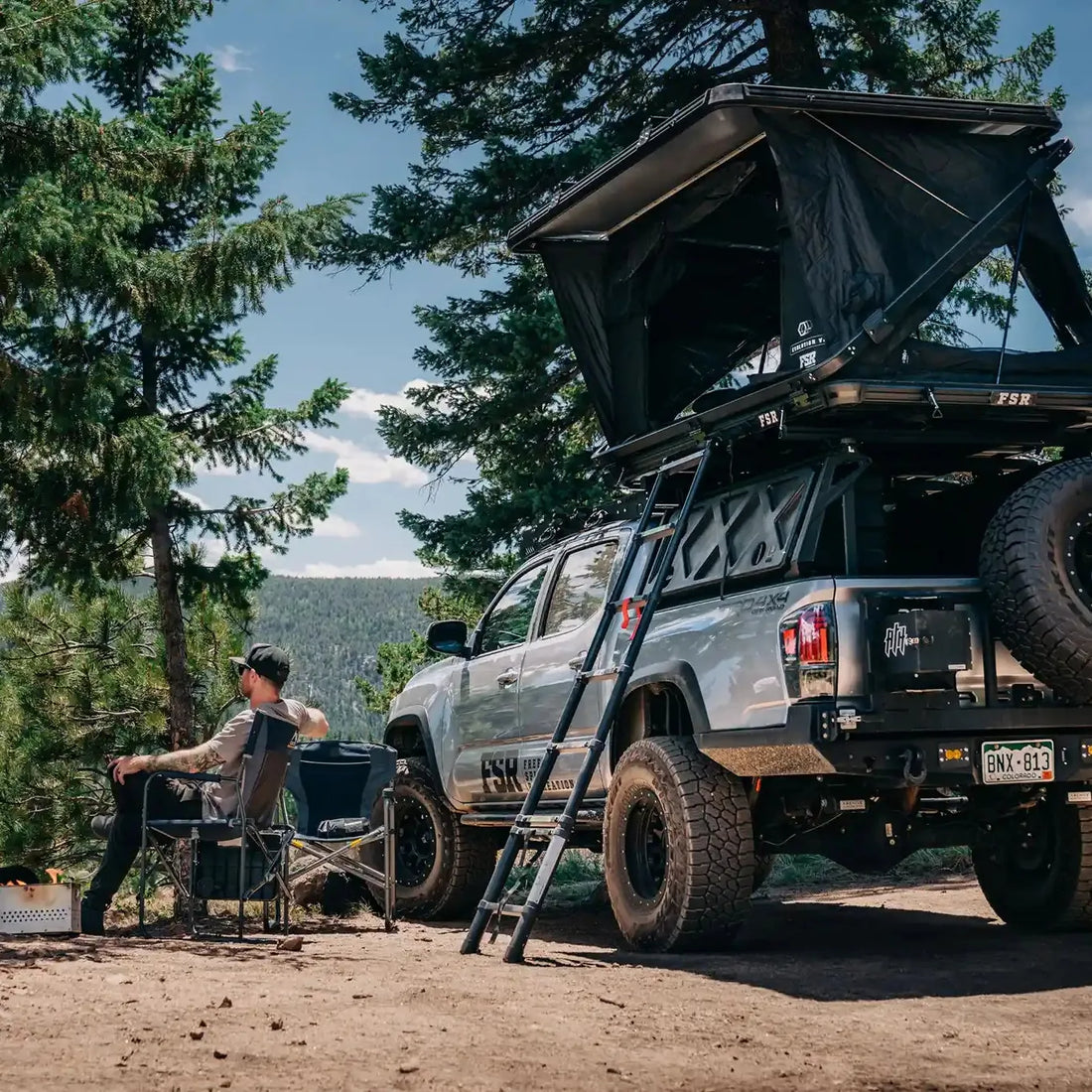 Camp setup with Free Spirit Evolution XL rooftop tent on a Tacoma in the forest