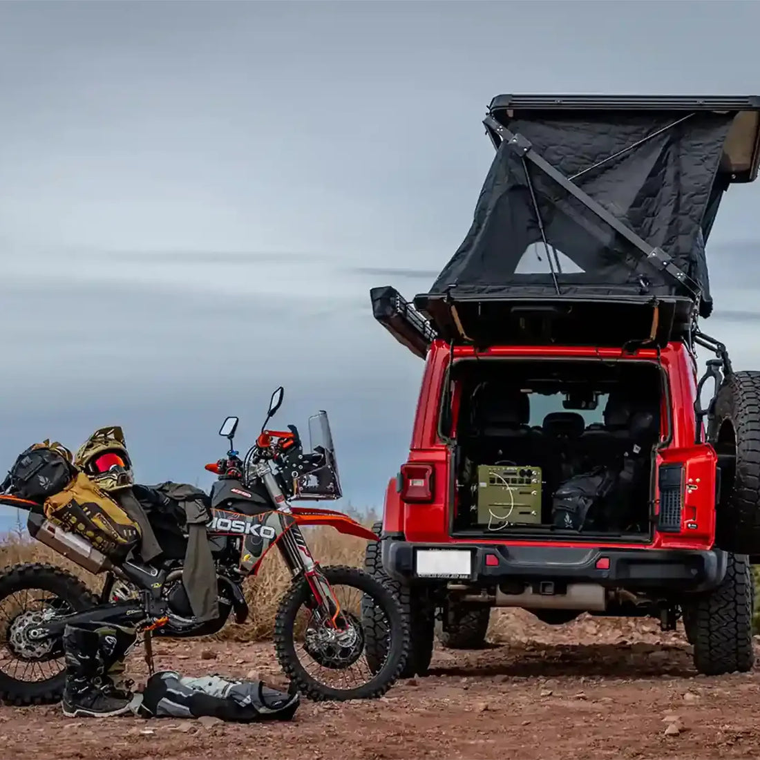 Red Jeep with Free Spirit Evolution XL rooftop tent and motorcycle at a desert campsite
