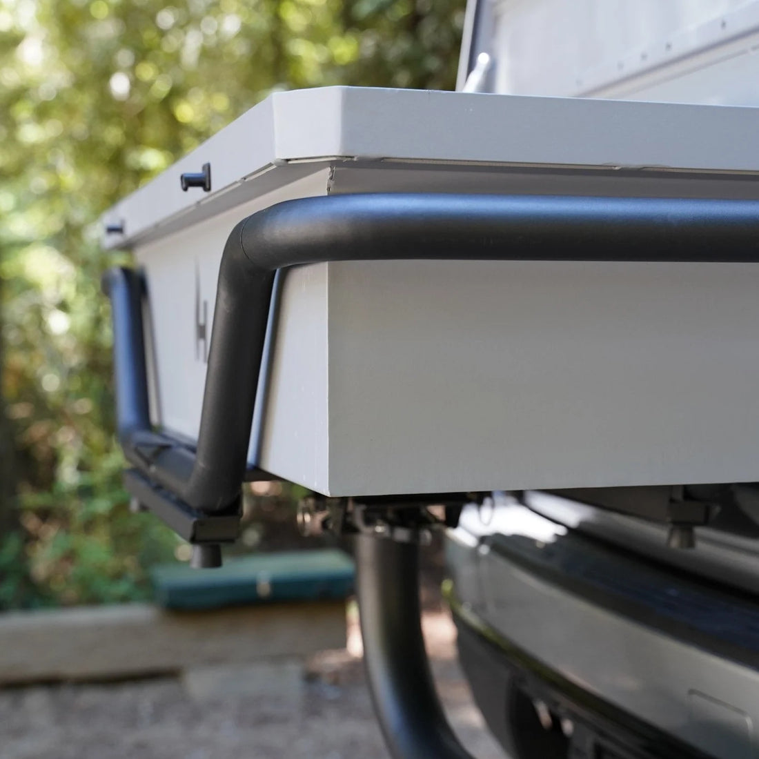 Back of a vehicle with a roof rack and storage box, outdoors.