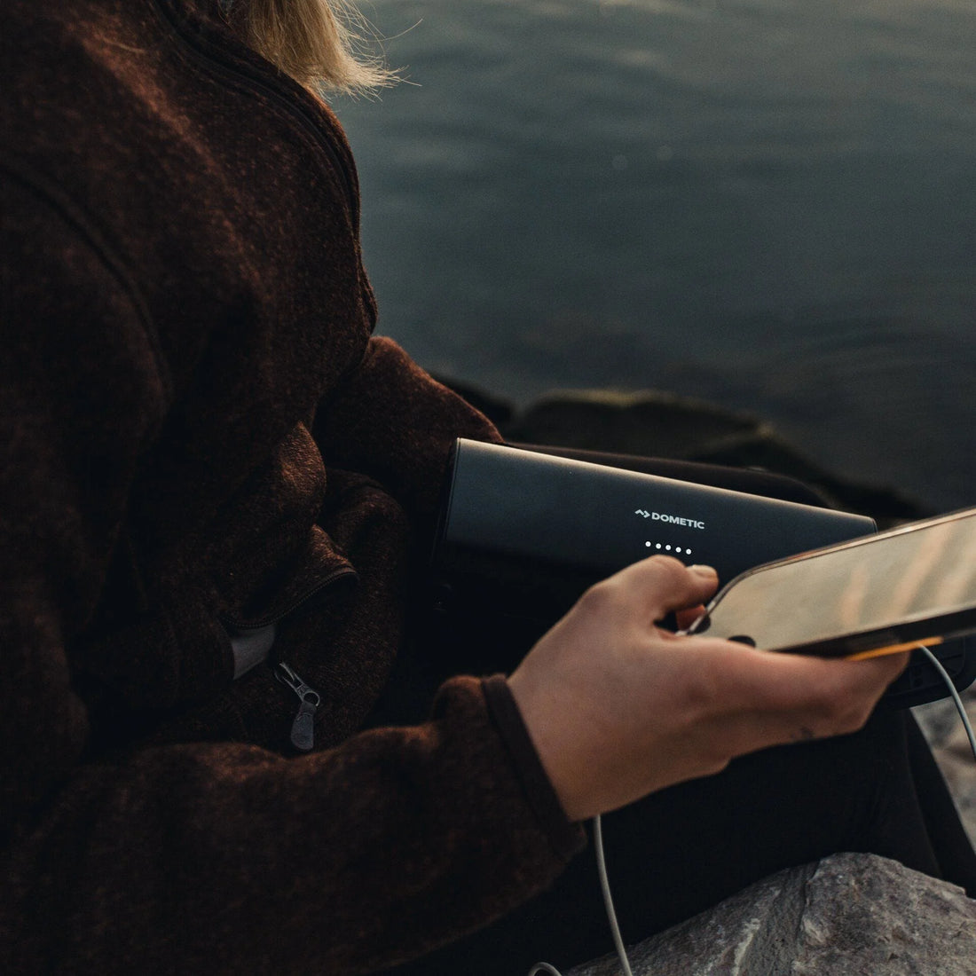 Person holding a Dometic product by a body of water