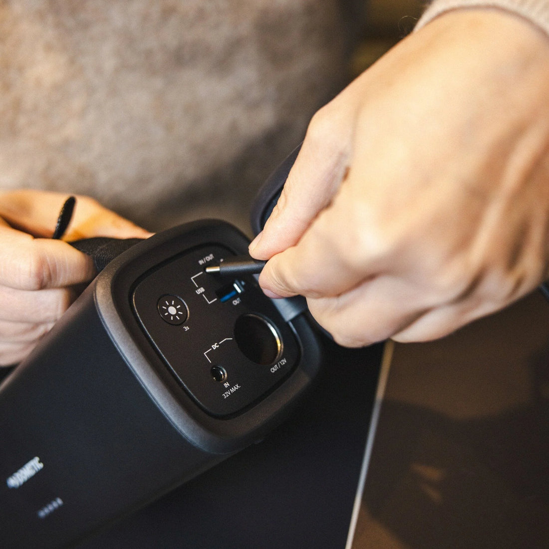 Person adjusting settings on a black electronic device with visible buttons.