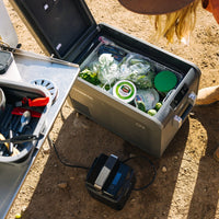 Portable refrigerator with food items on a camping site