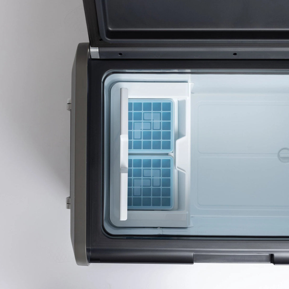 Open portable camping fridge freezer with removable ice trays, top-down view