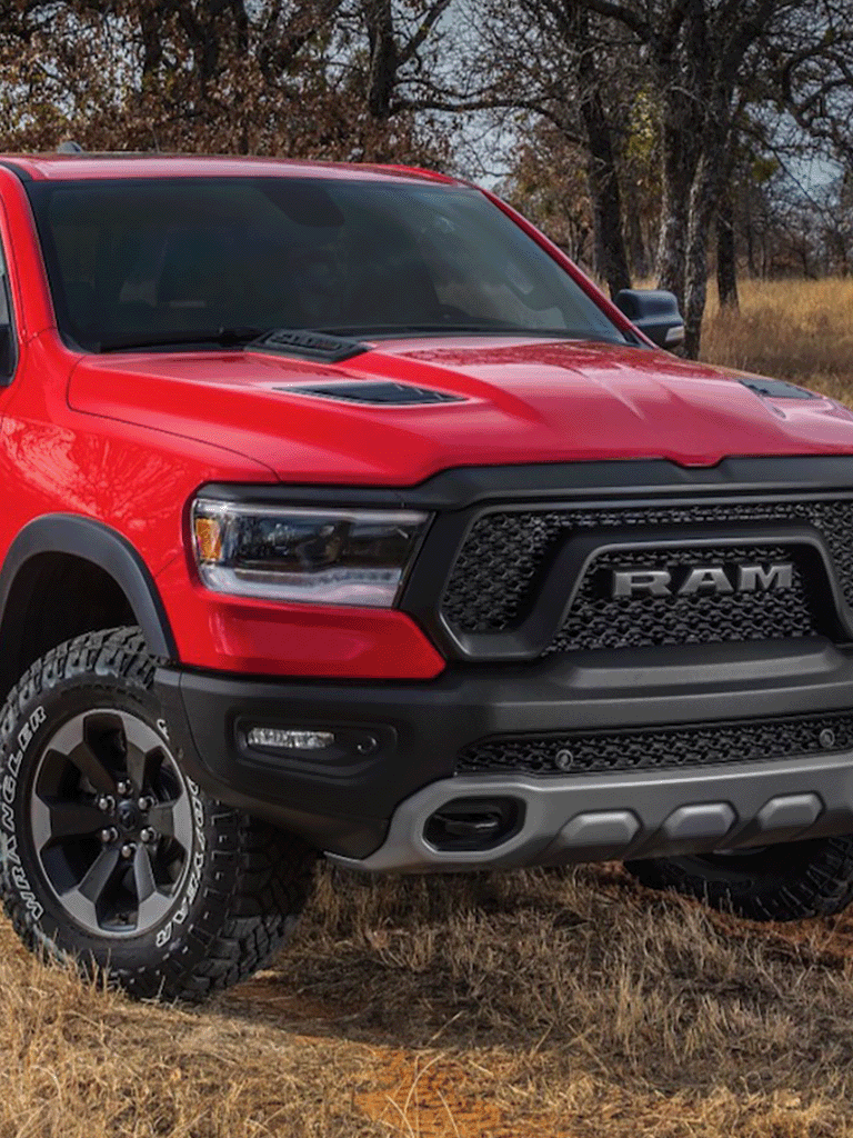 Front view of a red RAM off-road truck with all-terrain tires in a dry field.