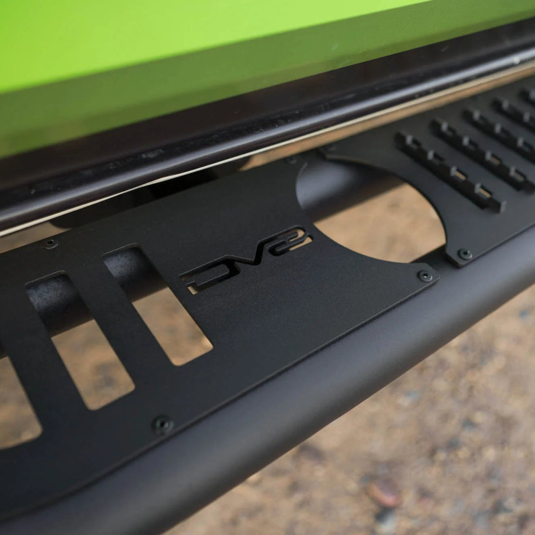 Close-up of a black side step bar on a green vehicle