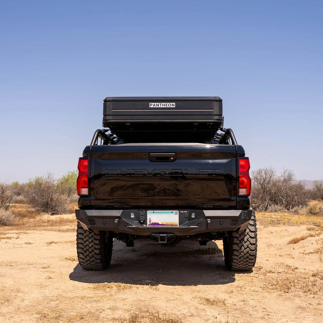 Black pickup truck with a bed cover in a desert landscape