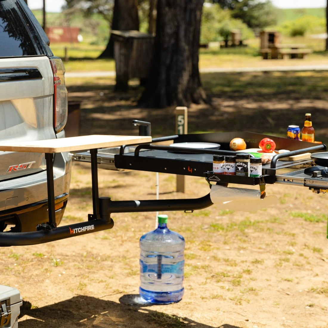 Outdoor setting with a truck tailgate extension featuring a portable stove and cooking items.