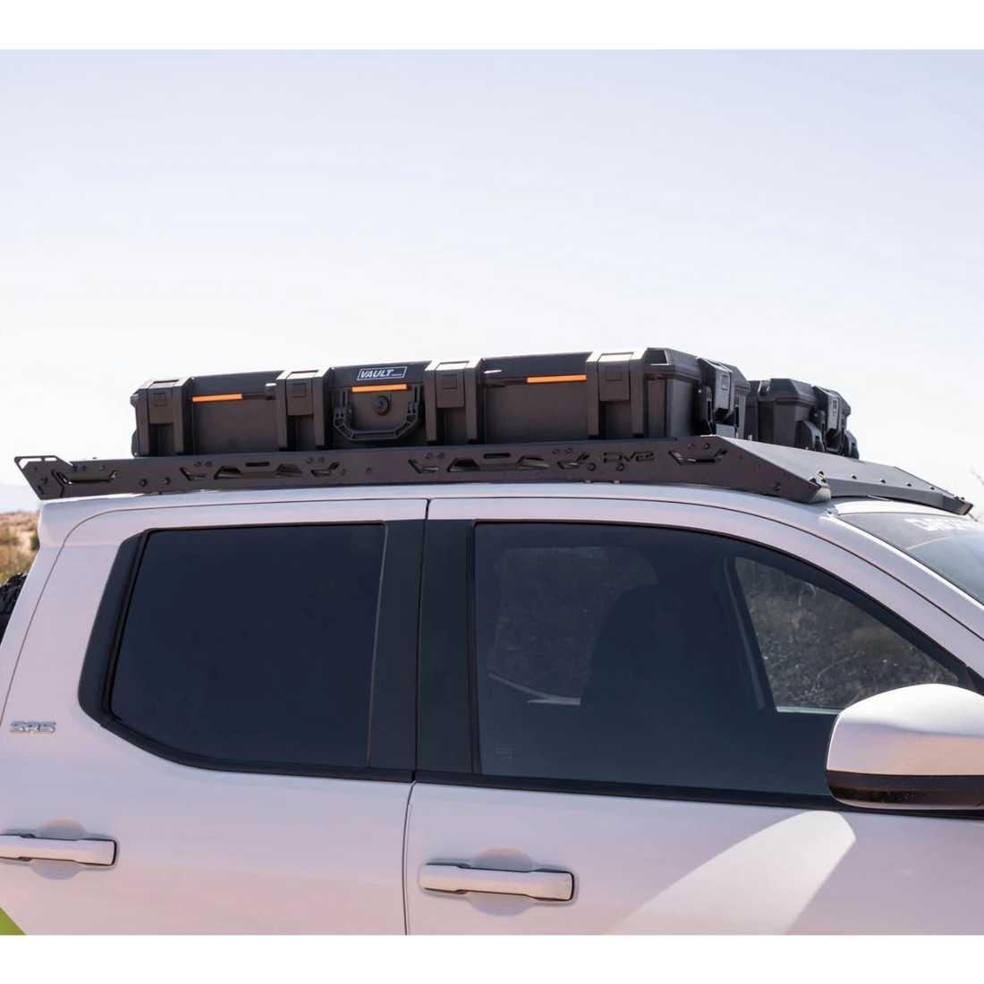 White SUV with roof storage boxes in a desert setting