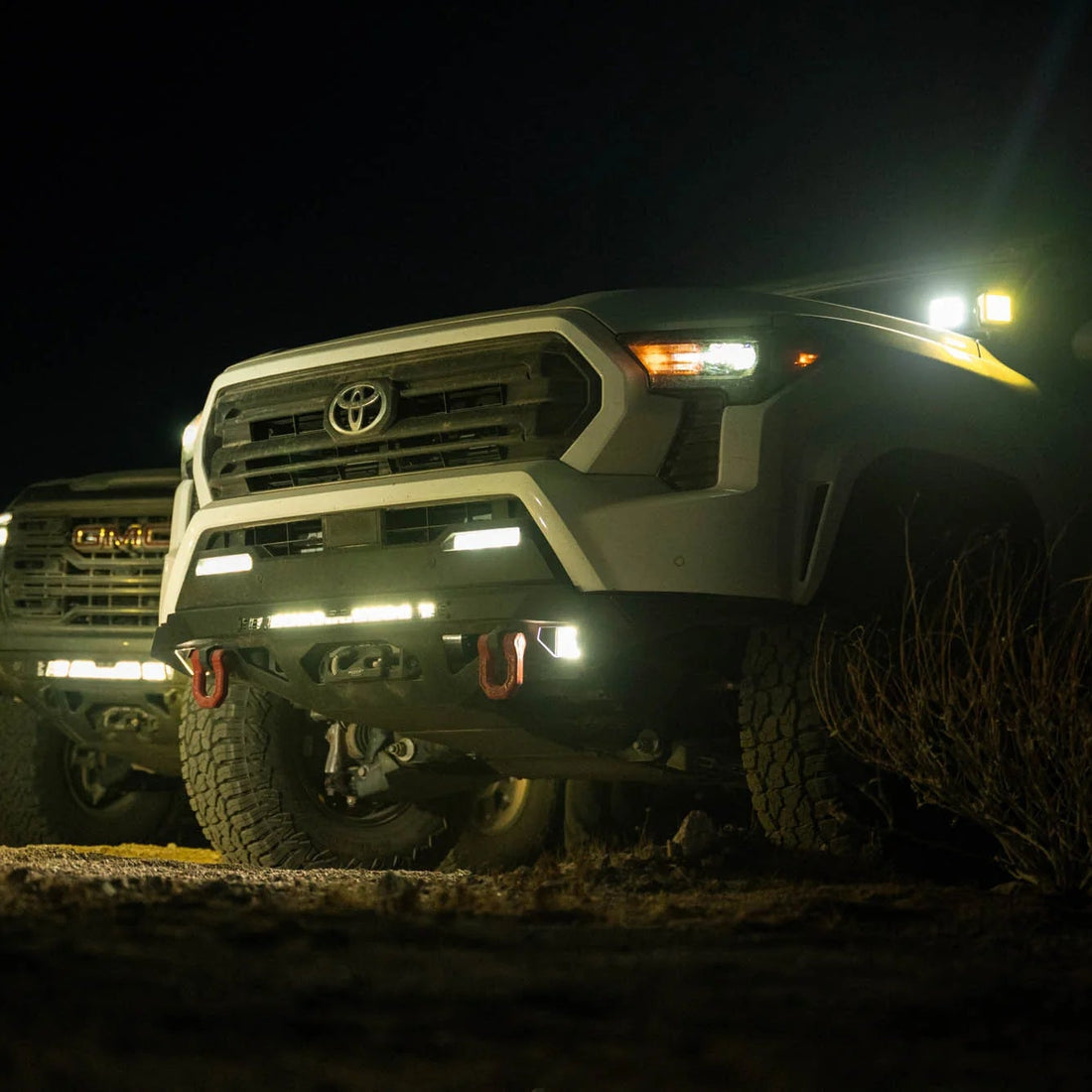 Toyota truck with headlights on at night in a desert setting