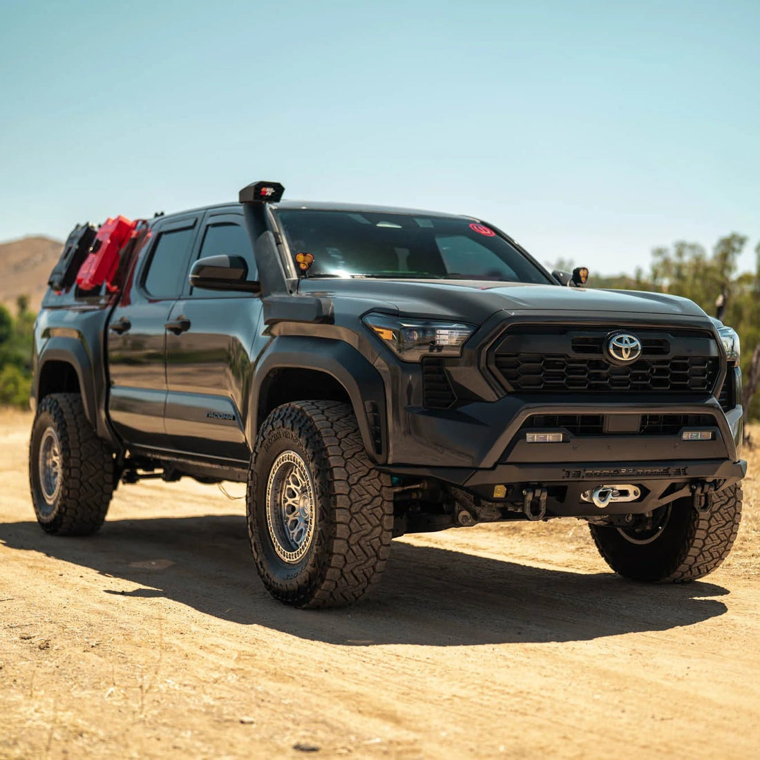 Black Toyota truck on a dirt road with mountains in the background