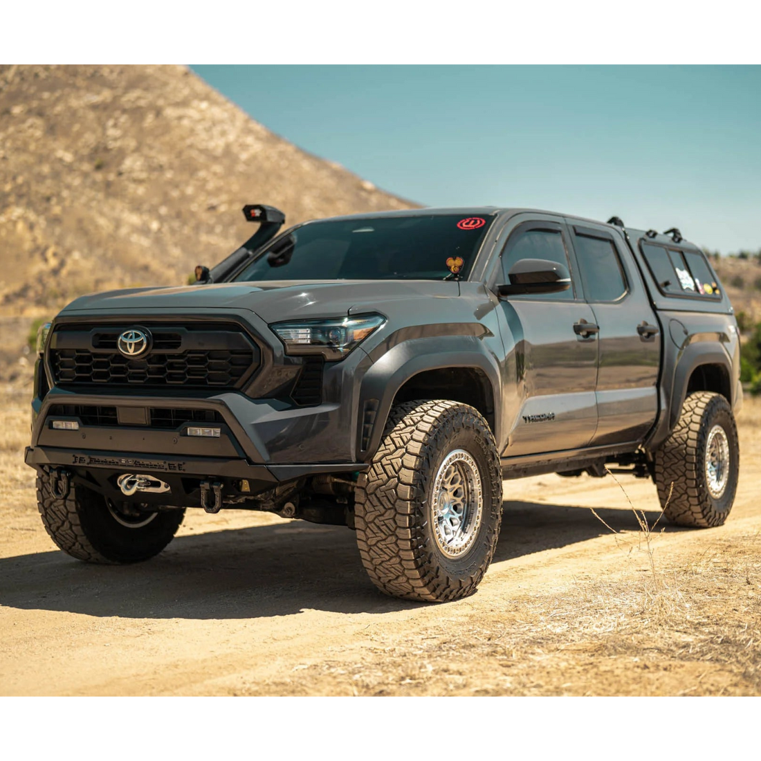 Gray Toyota truck on a dirt road with a mountainous background