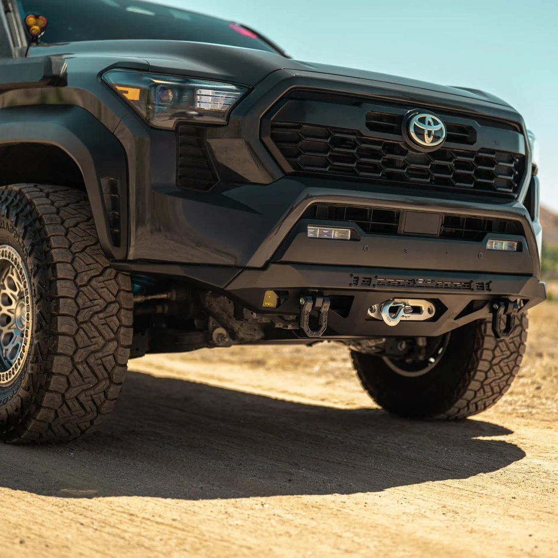 Black Toyota truck on a dirt road with a clear sky