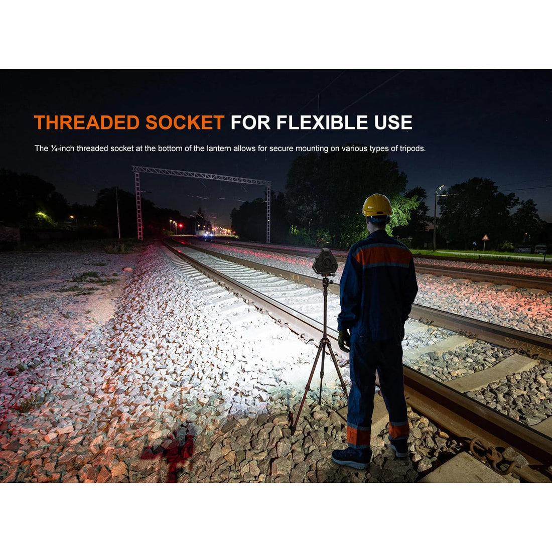 Fenix CP50R camping lantern on a tripod by its threaded socket, lighting railway tracks