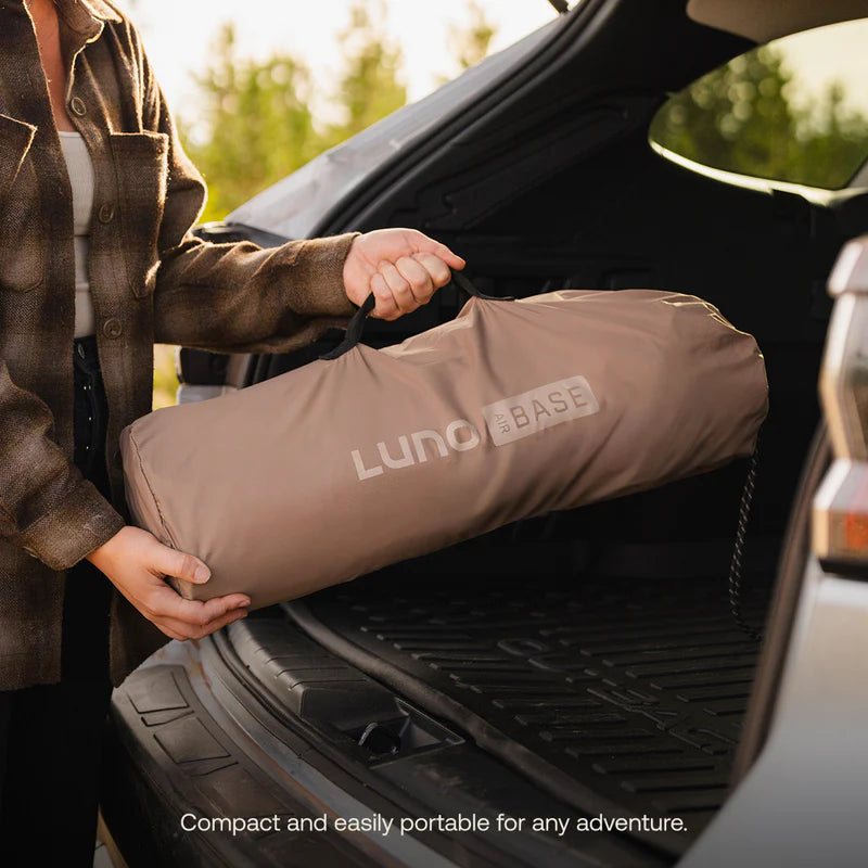 Person holding a rolled-up sleeping pad labeled &