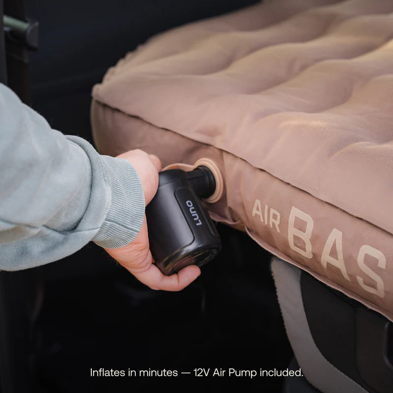 Person inflating an air mattress with a 12V air pump, featuring the brand &