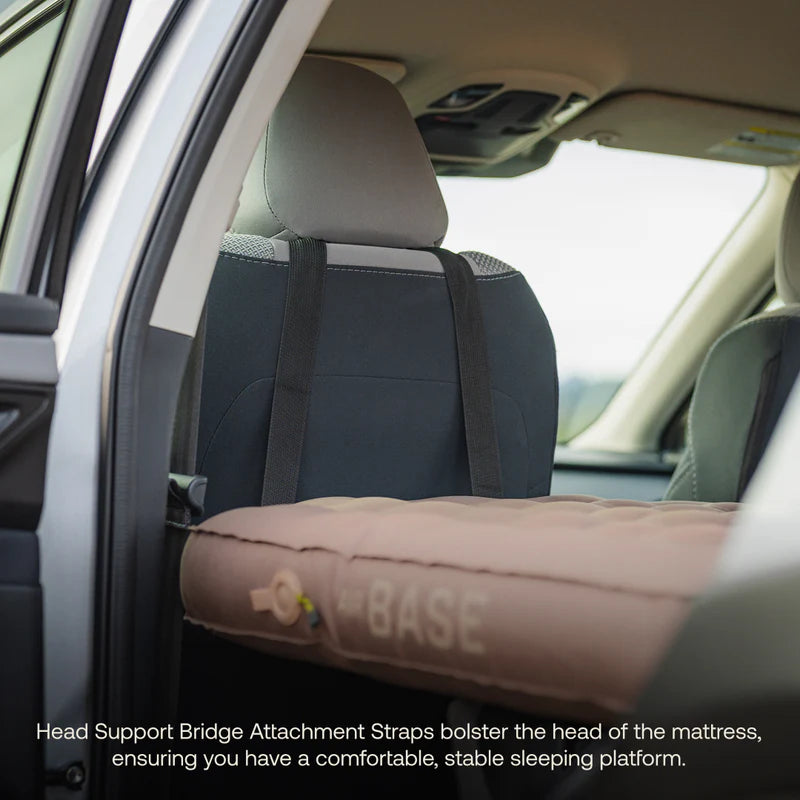 Car interior with a mattress and head support bridge attachment straps.