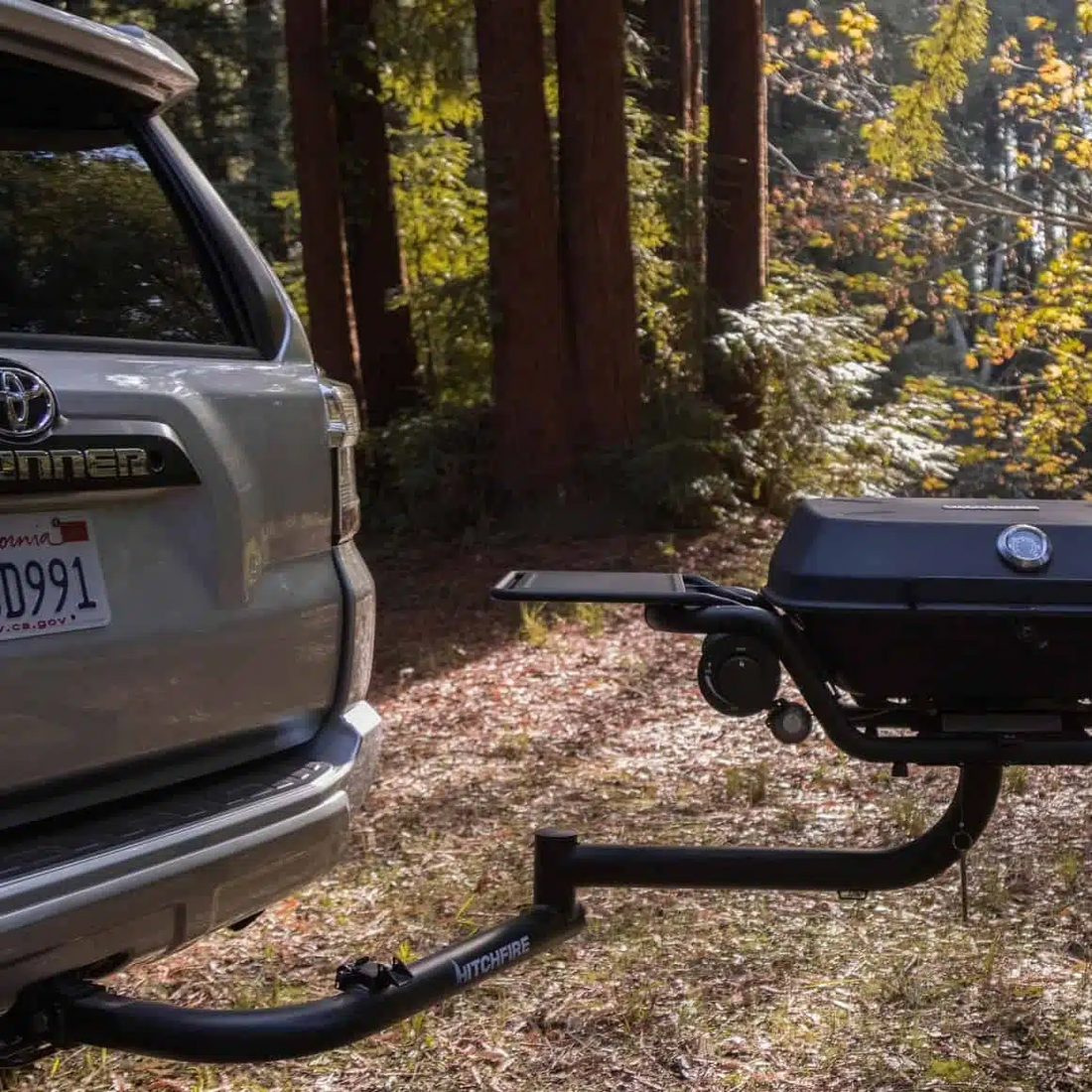 Gray Toyota SUV with a black bike rack attached, parked in a forested area.
