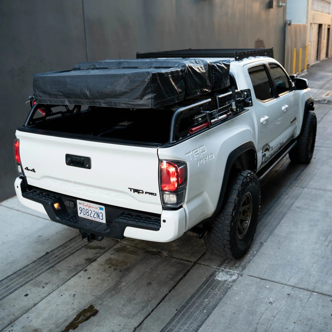 White Toyota Tacoma truck with a black tonneau cover on a city street.