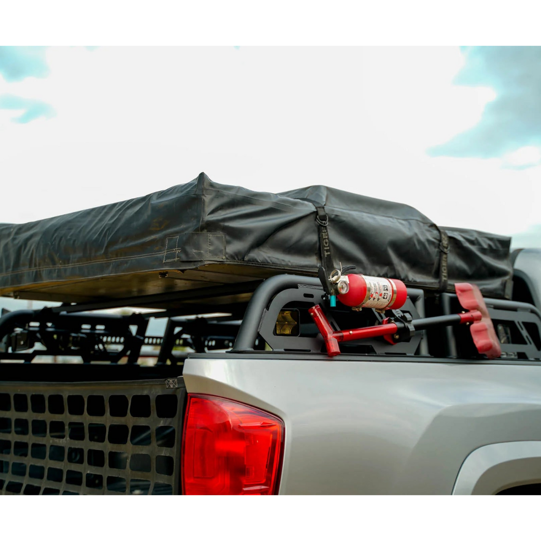 Roof rack on a vehicle with a tarp and fire extinguisher against a cloudy sky