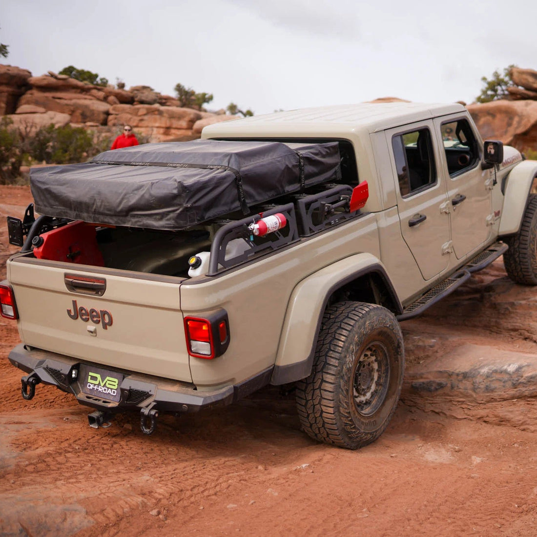 Beige Jeep truck with a roof rack and cargo bed cover in a desert landscape