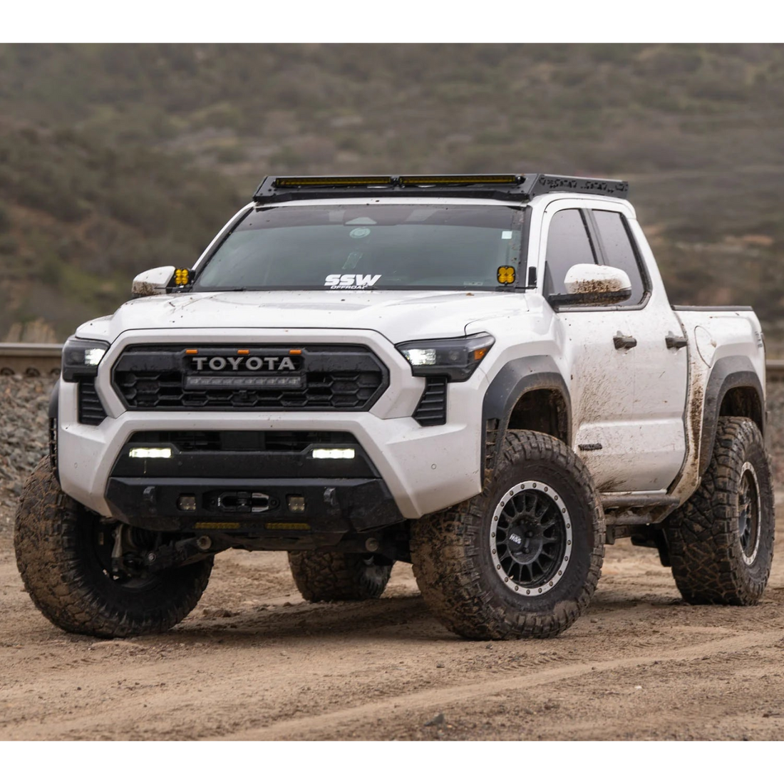 White Toyota truck on a dirt road with mountains in the background