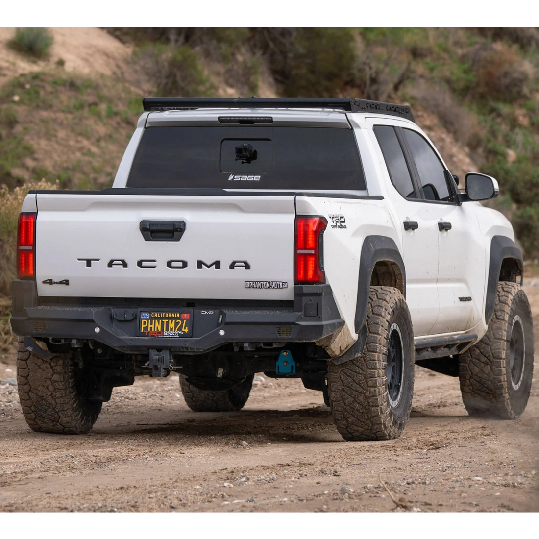White Toyota Tacoma truck on a dirt road with a rugged appearance