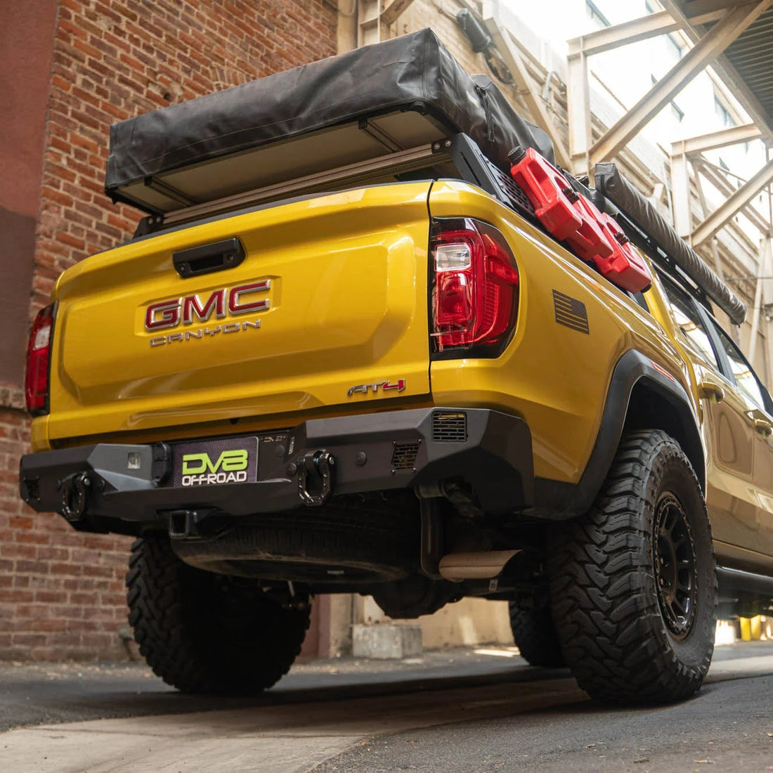 Yellow GMC Canyon truck with a black cargo bed in an urban setting.