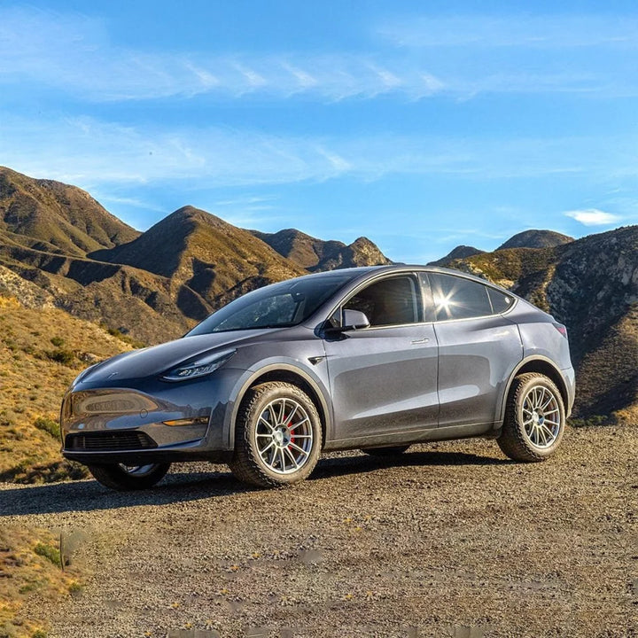 Silver Tesla Model Y parked on a dirt overlook in the hills
