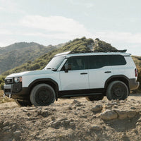 White SUV on a dirt road with mountains in the background