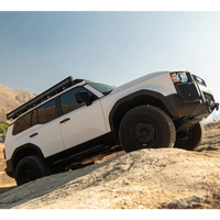 White off-road vehicle with black roof rack on a rocky terrain