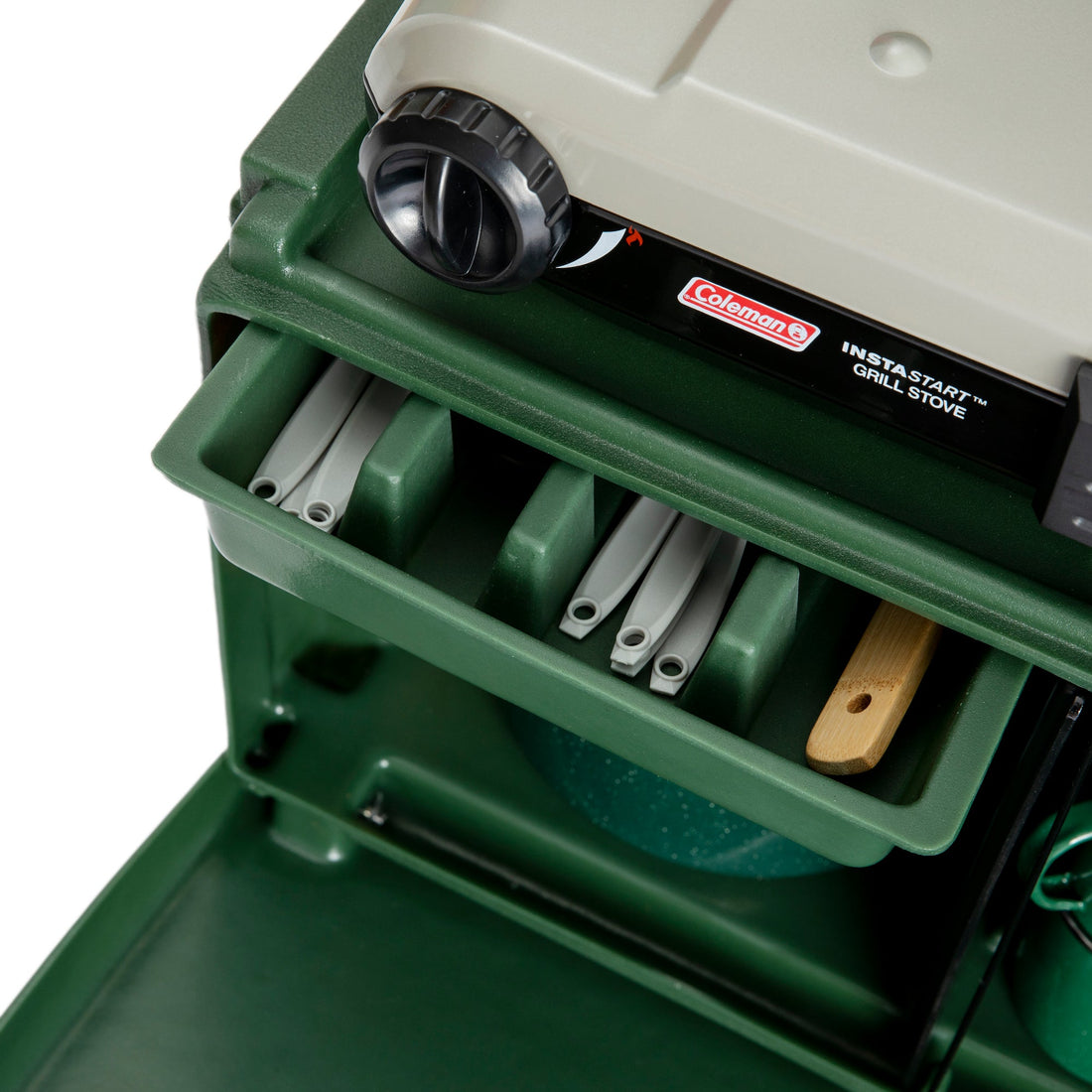 Close-up of a green Coleman InstaStart grill stove with tools inside.