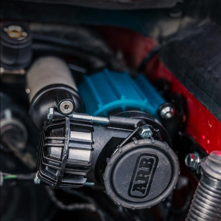 Close-up of a car engine with a black and blue component, featuring the ARB logo.