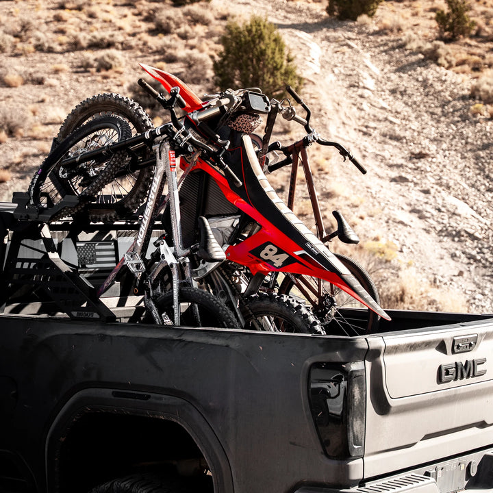GMC truck with dirt bike and mountain bikes on Big Days truck-bed rack in desert