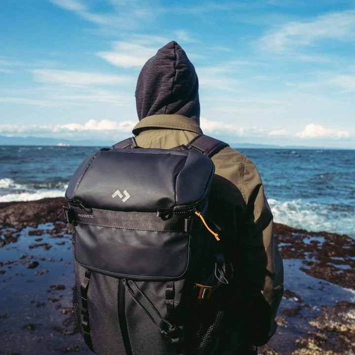 Dometic Unrestricted 24L Cooler Backpack worn by a hiker on a rocky coast